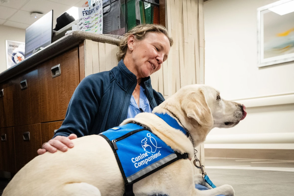 Peppi, a yellow Lab and official 'Canine Companion,' sits on the lap of OB-GYN Kristina Fraser in November at the HCA HealthONE Rose medical center in Denver.