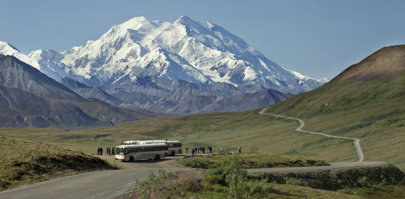 Denali National Park visitors, ferried by shuttle bus, take in a view of Denali, North America's tallest peak, on Aug. 9, 2012. Seen in the background is the sole road that runs through the park. Denali is unusual among U.S. national parks for its strict limits on vehicle traffic. Vehicle use is restricted beyond the first 15 miles of the park's 92-mile road, and most of it is by shuttle bus. A new rule will increase the number of vehicles allowed past the road's first 15 miles.