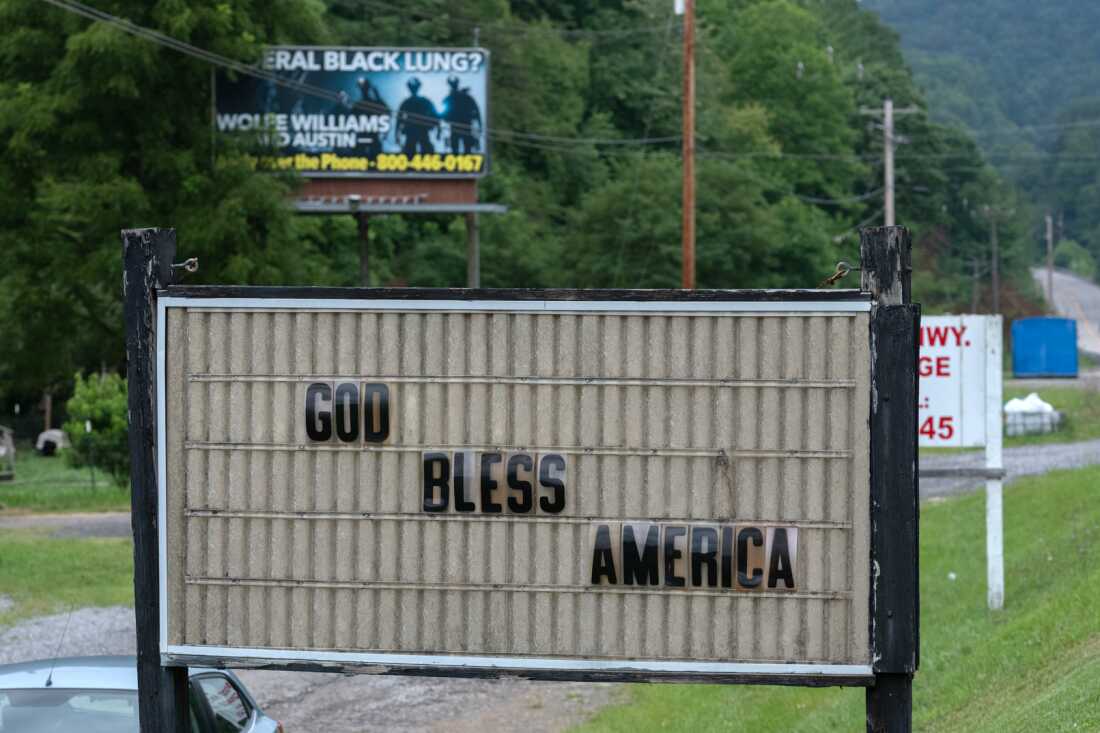 A billboard advertising assistance with Black Lung claims overlooks the Calvary Baptist Church along the Dickenson Highway near Clintwood, Virginia.