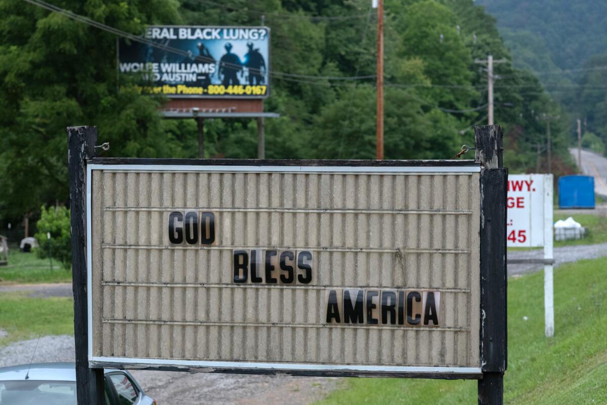 A billboard advertising assistance with black lung disease claims overlooks the Calvary Baptist Church along the Dickenson Highway near Clintwood, Va.