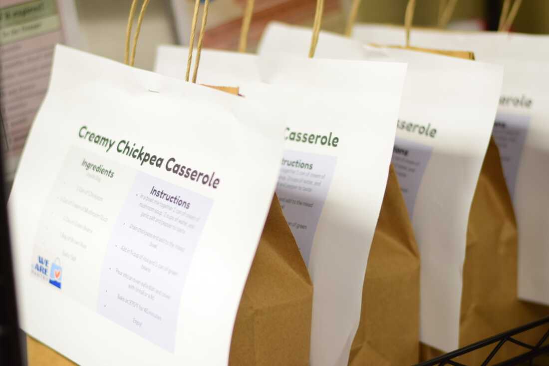 An image of several paper bags filled with ingredients for "chickpea casserole," with recipe and instructions stapled to the bag. It lines the shelves at the WE cARE food pantry at Penn State Harrisburg. The food pantry offers students pre-assembled kits containing all the ingredients they need to prepare a meal.