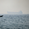 A motorboat cruises with a tanker in the background, in the Strait of Hormuz, off the coast of the United Arab Emirates, on February 25, 2026. Tanker traffic through the strait has essentially come to a halt after Iran declared the strait closed following attacks on Iran by the US and Israel.