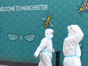 People wear protective suits as they walk along Market Street in the near-deserted city center in Manchester, England, on April 15, 2020, during the nationwide lockdown to combat the coronavirus pandemic.