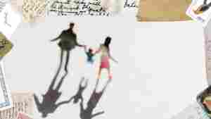 A blurry photograph of a family walking and holding hands, as seen from a high angle. Two parents walk, holding the hands of their child who walks between them. The photo has a dreamy quality. 