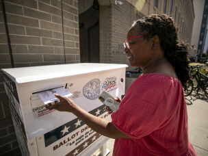 Darlene Jenkins slides her parents' ballots into a dropbox in Denver during the Colorado primary elections Tuesday.