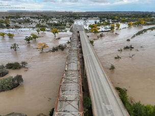 An aerial image of the Shiprock Bridge spanning over a flooding San Juan River.