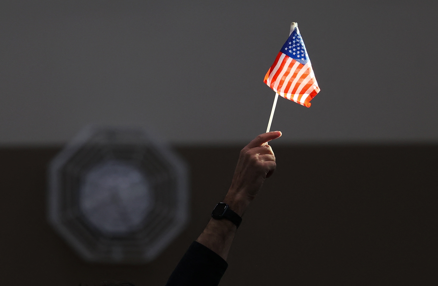 An election worker raises a U.S. flag while assisting voters at a polling station in Las Vegas on Election Day, Nov. 5, 2024. (AFP via Getty Images)