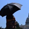 A person uses an umbrella as they walk near Capitol Hill in Washington, D.C., on Friday. The United States is experiencing its first significant heat wave of the year, across the Great Plains and expanding into parts of the Midwest and Great Lakes over the weekend, according to the National Weather Service.