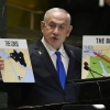 Prime Minister of Israel Benjamin Netanyahu hold signs as he addresses the 79th session of the United Nations General Assembly on Friday.
