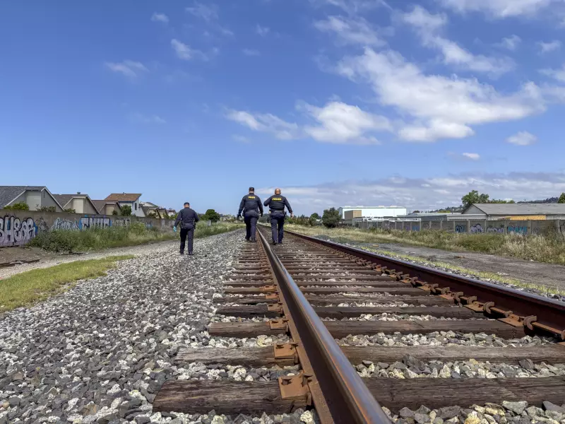 Police walk down a train line toward people of interest at the scene of cut AT&T wires.