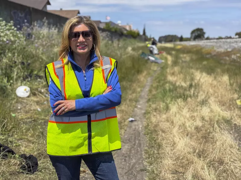 Susan Santana, president of AT&T West, stands by a path along a railroad in Hayward, Calif., where cables were cut.