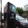 A cyclist rides past a Chicago Parking Meters LLC pay station in the 1100 block of West 18th Street in Chicago’s Pilsen neighborhood on May 15, 2025.