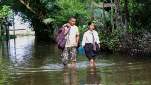A school girl and her father wade through floodwaters in Alengmora village in Jorhat, India, Monday, Aug. 10, 2026.