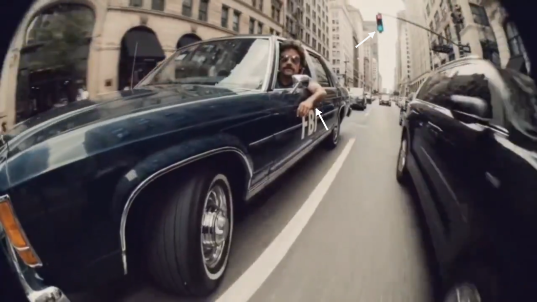 A video still from the FBI promotional shows several tell-tale signs of AI image generation. The arm of the driver appears shrunken and both the red and green lights are lit on the stoplight.