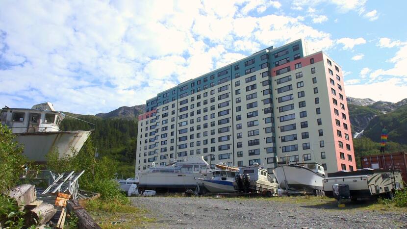 The resident apartment building in Whittier, Alaska towers over a boat parking lot on a summer day of 2021.