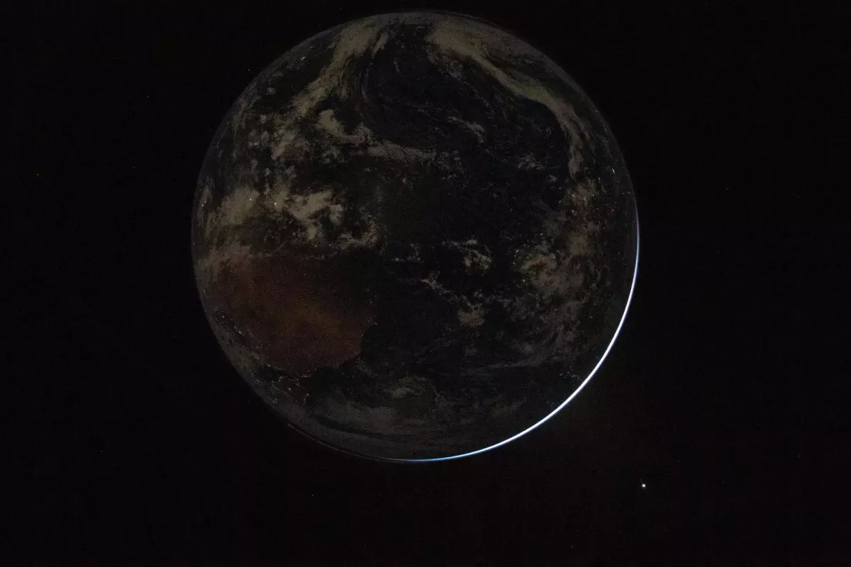 A view of a backlit Earth taken by NASA astronaut and Artemis II Commander Reid Wiseman from one of the Orion spacecraft's window after completing the translunar injection burn on April 2, 2026.