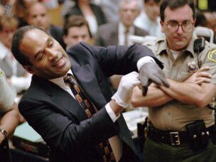FILE - In this June 15, 1995 file photo, O.J. Simpson, left, grimaces as he tries on one of the leather gloves prosecutors say he wore the night his ex-wife Nicole Brown Simpson and Ron Goldman were murdered in a Los Angeles courtroom.