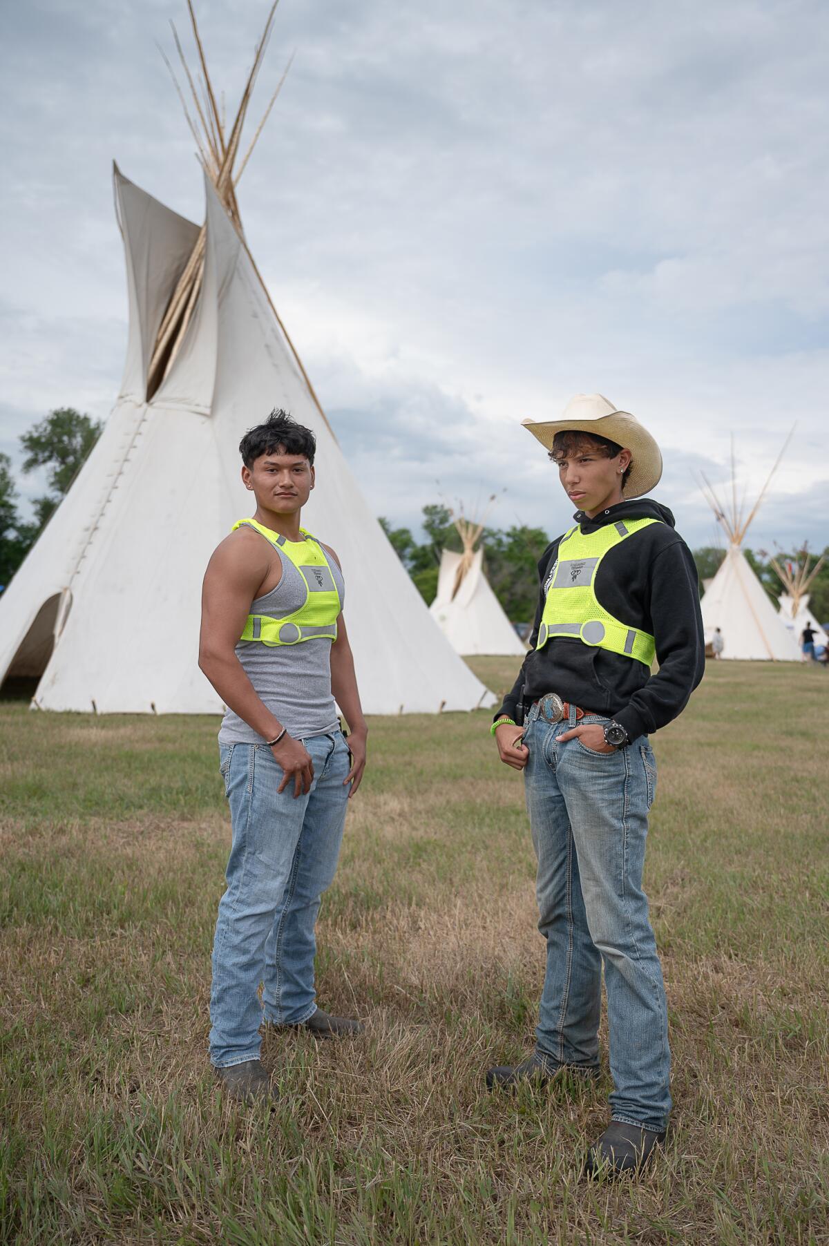 Champion Marquez and his friend Elijah Wallowing pose in front of a tipi in the encampment.