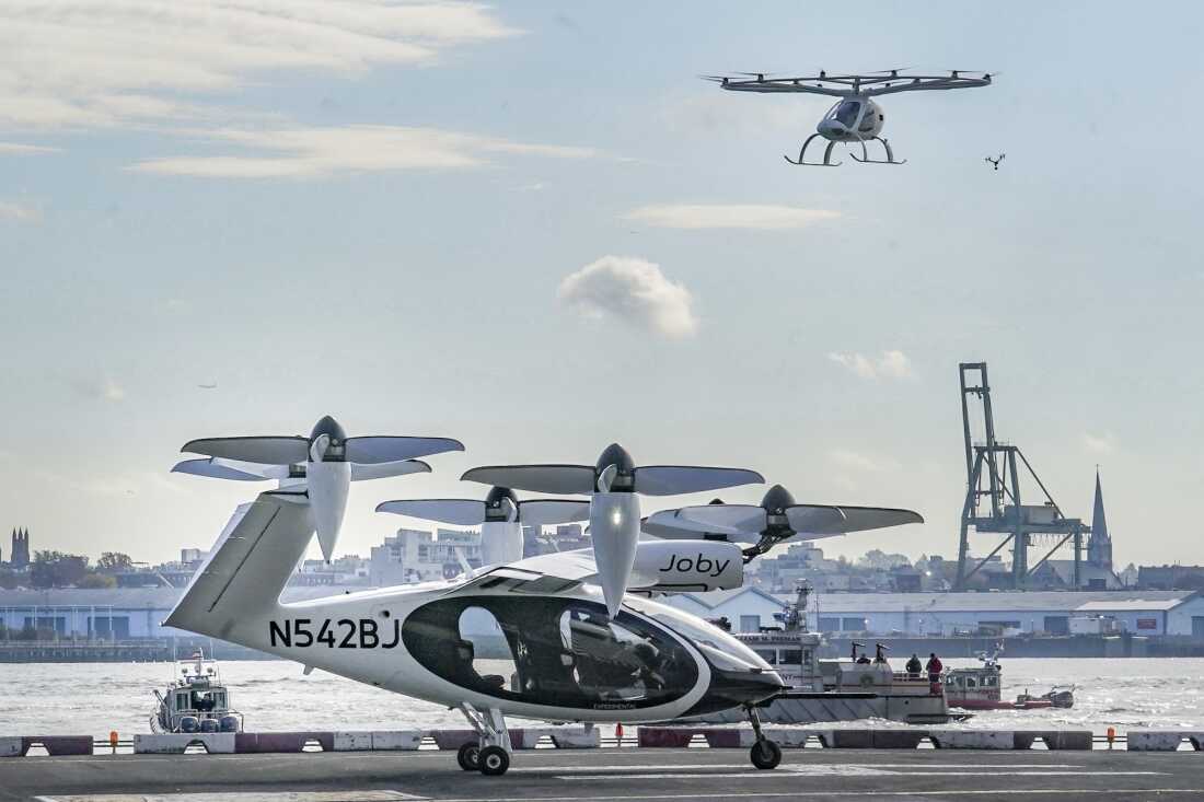 An electric vertical takeoff and landing (eVTOL) aircraft, flies above the Joby eVTOL aircraft, during a demonstration of eVTOLs Nov. 13, 2023, in New York.