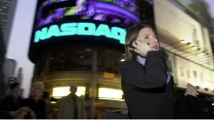 In this photo from 2000, a woman holding a cellphone to her ear walks past the illuminated Nasdaq sign in New York City's Times Square.
