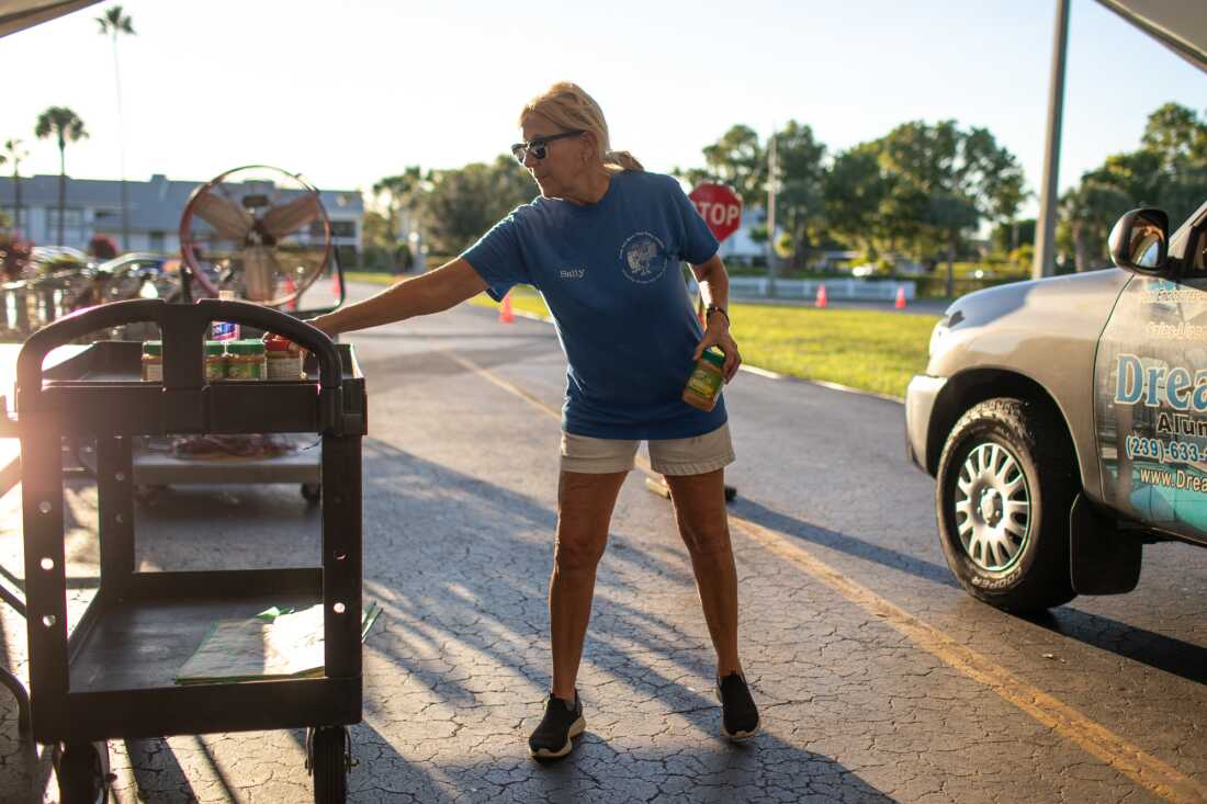 Sally Scott hands out food at the South Fort Myers Food Pantry in Florida. The group is seeing more people struggling to afford food amid high housing costs."