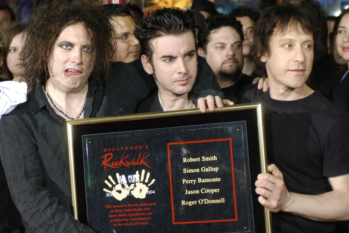 Robert Smith, left, Simon Gallup, center, and Perry Bamonte of British rock group The Cure hold a plaque after being inducted into Hollywood's Rockwalk in Los Angeles, Friday, April 30, 2004.