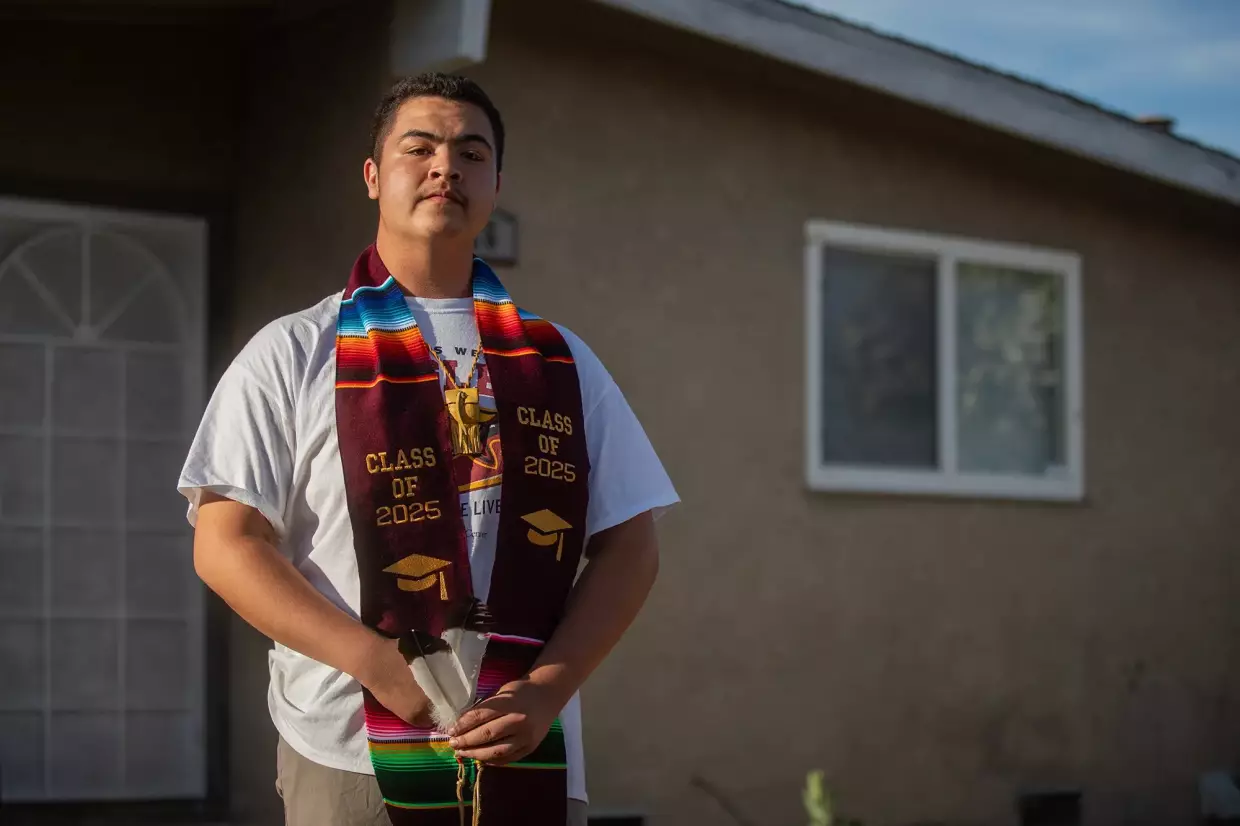Ethan Molina wears his graduation stole as he stands in front of his home in Fresno on May 14, 2025. Molina, a member of the Pascua Yaqui Tribe in Arizona and a senior at Clovis West High, was told by the school district that he could not wear the stole to his graduation ceremony.