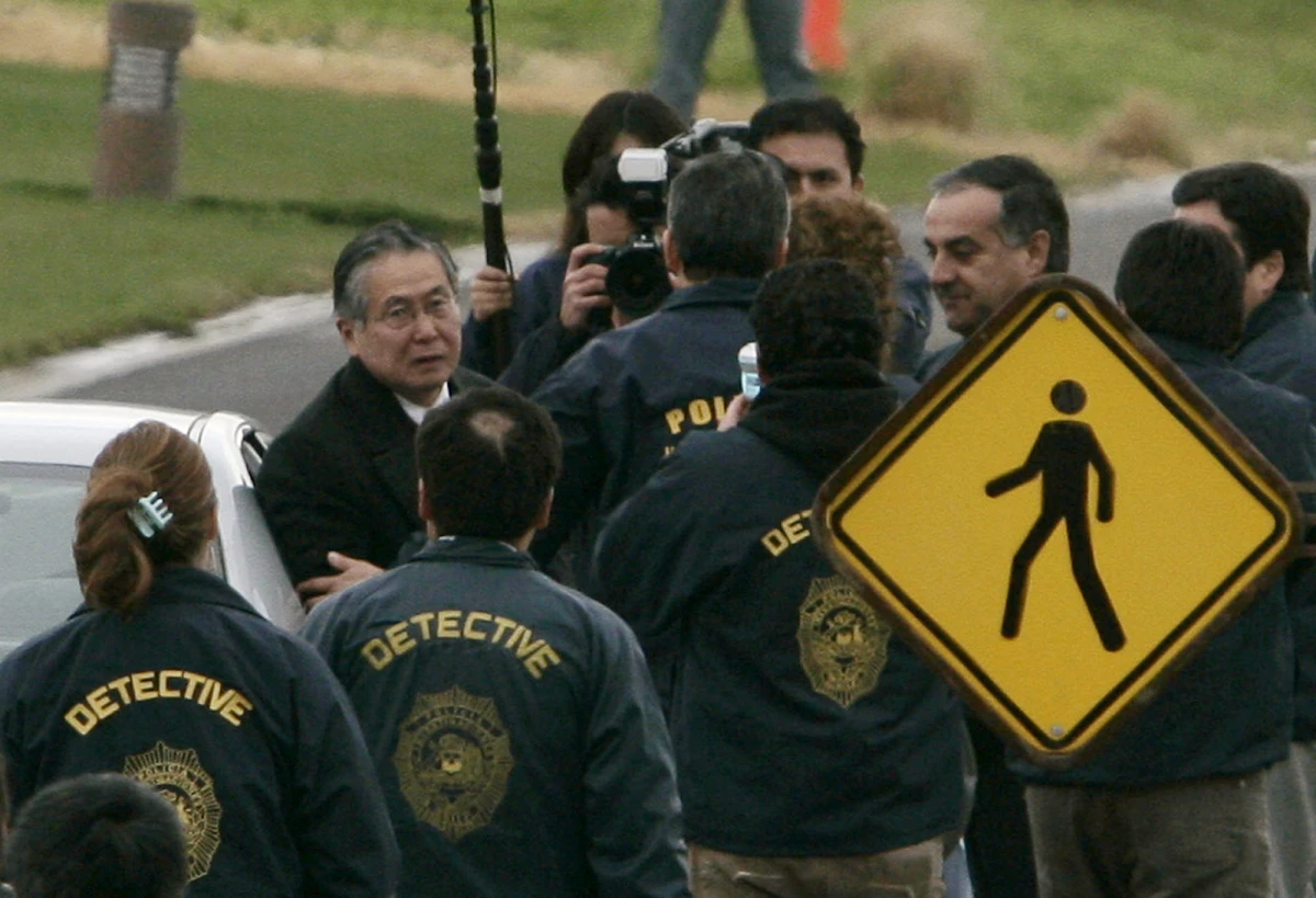 Chilean police officers surround former Peru's President Alberto Fujimori (left) as he leaves his house in Santiago to be extradited to Peru to face human rights and corruption charges, early Sept. 22, 2007.