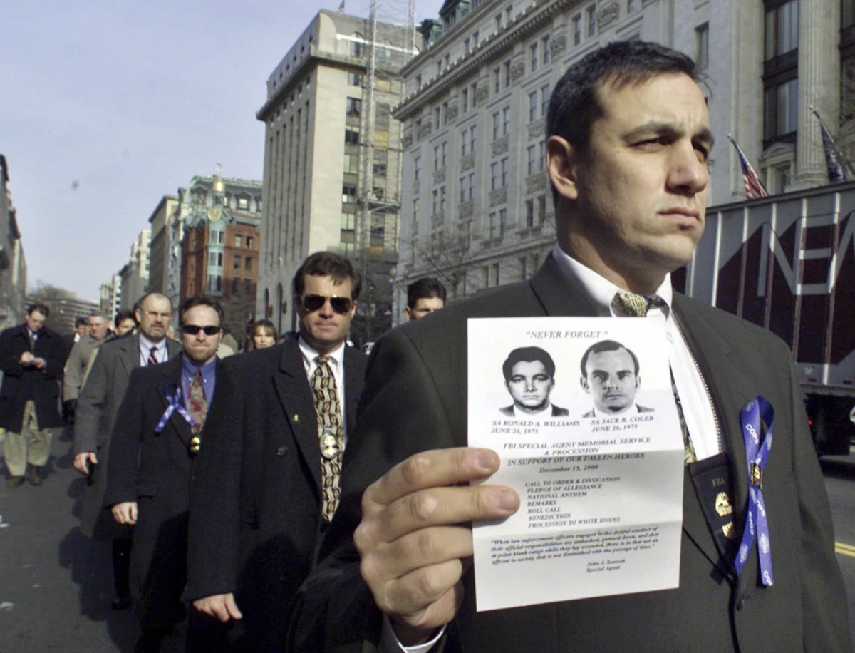 An unidentified FBI agent, one of nearly 500 current and retired FBI agents who protested clemency for Leonard Peltier on Dec. 15, 2000, marches toward the White House holding an image of two FBI agents, Ron Williams and Jack Coler, who were killed on the Pine Ridge Indian Reservation in South Dakota in 1975.