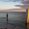 A person fishes next to a broken pier.