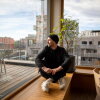 Sebastian Schublach sits next to the windows of his buildings shared kitchen and hosting space. Schublach has lived in this climate-friendly affordable apartment in Vienna for six years with his wife and two kids. At top: Schlubach sits in the building’s light filled rooftop kitchen and dining room.