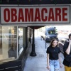 A young man and woman walk on a city sidewalk under a sign that says