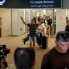TZAFRIA, ISRAEL - SEPTEMBER 30: A passenger raises his arms in relief as he walks through the domestic arrivals doors with his dog and luggage at Ben Gurion Airport on September 30, 2026 in Tzafria, Israel. A flydubai flight from Dubai to Tel Aviv was diverted to Saudi Arabia after a violent altercation in the cockpit.