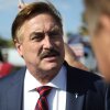 MyPillow CEO Mike Lindell arrives at a gathering of Donald Trump supporters in Palm Beach, Florida, on April 4, 2023. Photographed from about the chest up, he's wearing a blue suit jacket, a white shirt and a red and blue tie.