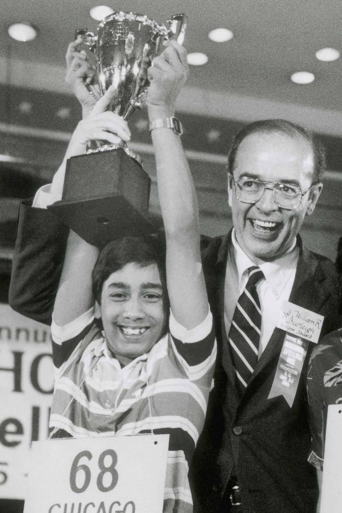 Balu Natarajan, an 8th grade student at Jefferson Junior High School in Woodbridge, Ill., holds his trophy with the aid of William R. Burleigh, vice president of Scripps Howard Newspapers, sponsor of the National Spelling Bee, after he won the competition in Washington, on June 6, 1985.