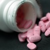 A pill bottle with pink pills spilling out is shown. 