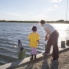 Amanda Devecka-Rinear and her young daughter stand at the edge of their front yard, which borders a bay. They are skipping gravel-like stones on the water.