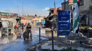 A worker walks through the muddy streets of the Jaramana Camp on the edge of Damascus, Syria. About 13,000 Palestinian refugees live in the camp.