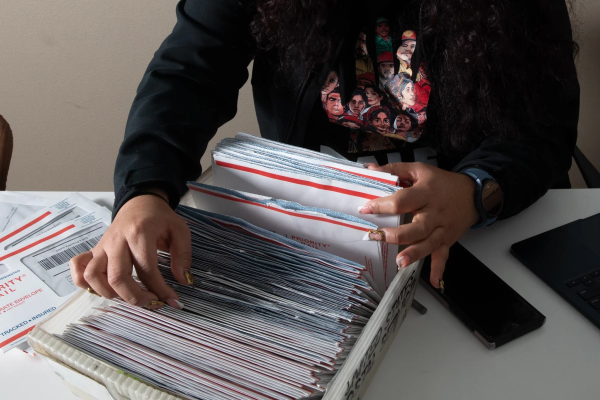 Martinez sorts through work authorization cards that have arrived for DALE applicants. The recipients will have protection from deportation for the next four years.