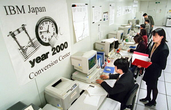 Engineers with IBM Japan sit at a row of computers in a conference room, working to convert computer software for their clients, including banks and local governments, to protect against the potentially destructive "millennium bug" computer problem.