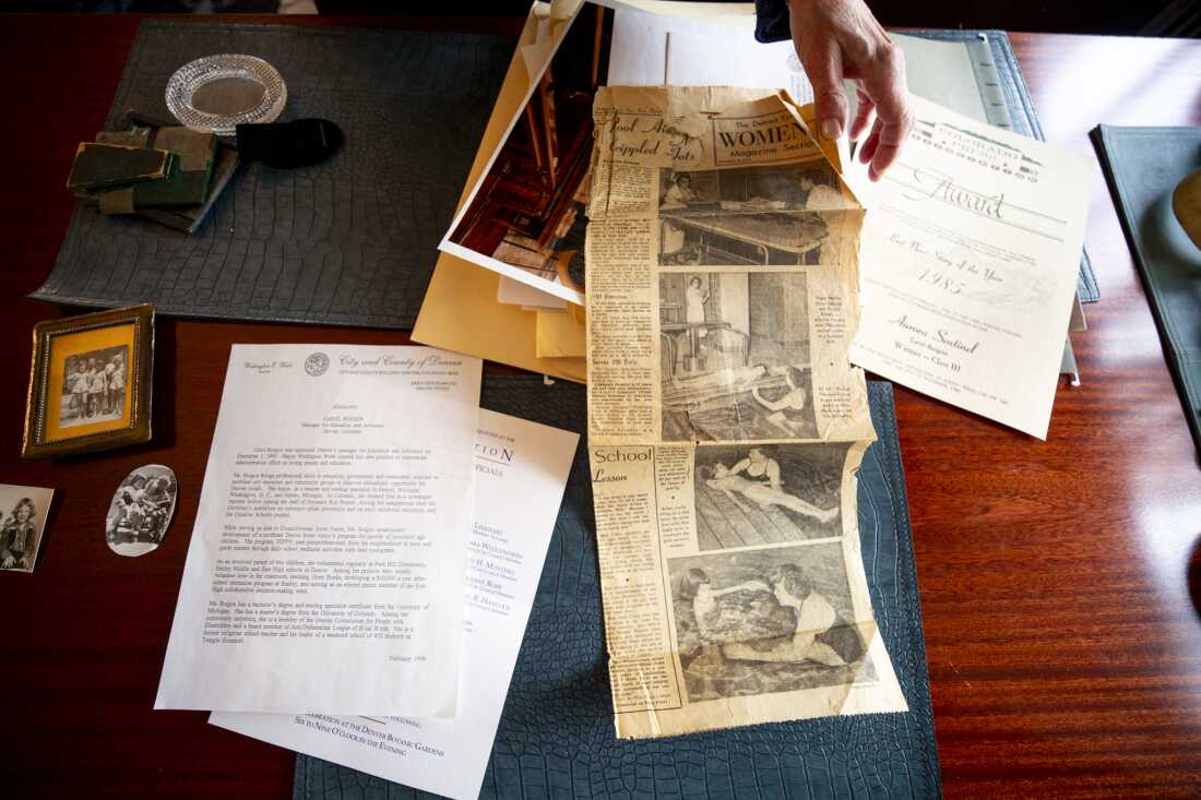 Carol Boigon, a former Denver City Council member and polio survivor, shows memorabilia from her life and career. The newspaper clipping from The Detroit Times shows a young polio patient receiving aquatic physical therapy.