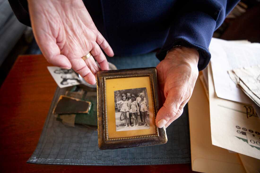 Carol Boigon, a member of Colorado Chooses Vaccines, holds a 1950s-era photo of her (left) and other children outside in Detroit, after her hospitalization for polio. Her right arm, which never fully regained function, is supported by a brace.