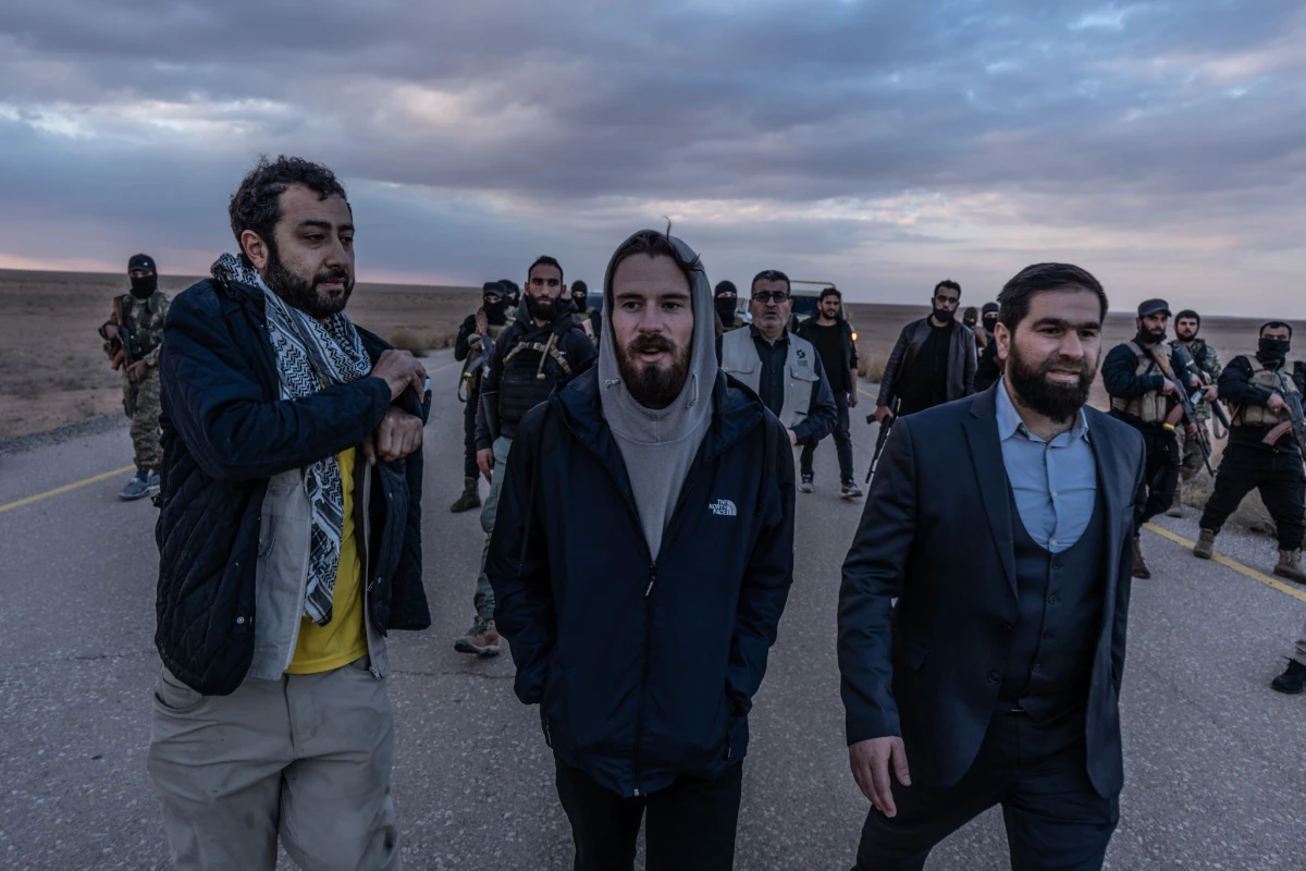 Timmerman (center) walks with Mouaz Moustafa (left) and an interim Syrian government official before his handover to U.S. forces in southern Syria on Friday.