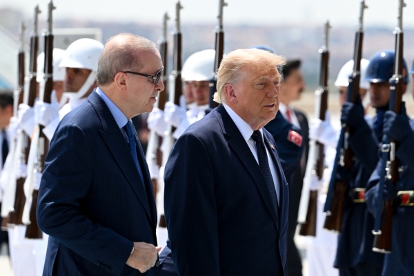 Turkish President Recep Tayyip Erdogan and President Trump walk side by side upon Trump's arrival at Etimesgut Air Base in Turkey on July 7. Rows of people wearing military-style uniforms and holding rifles stand behind the two men.