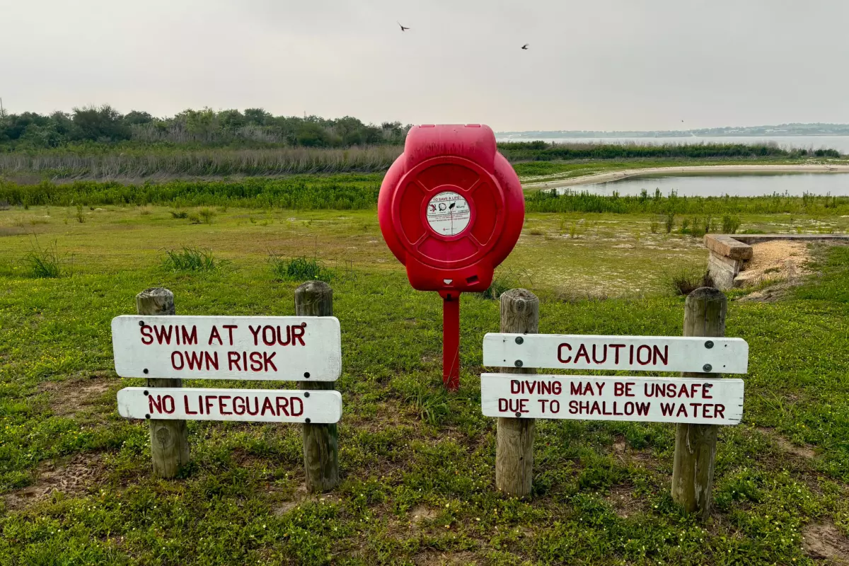 Lake Corpus Christi dropped below 10 percent full in March, the lowest on record since it was first filled in the late 1950s. Signs about swimming sit far from the water's edge on April 28.