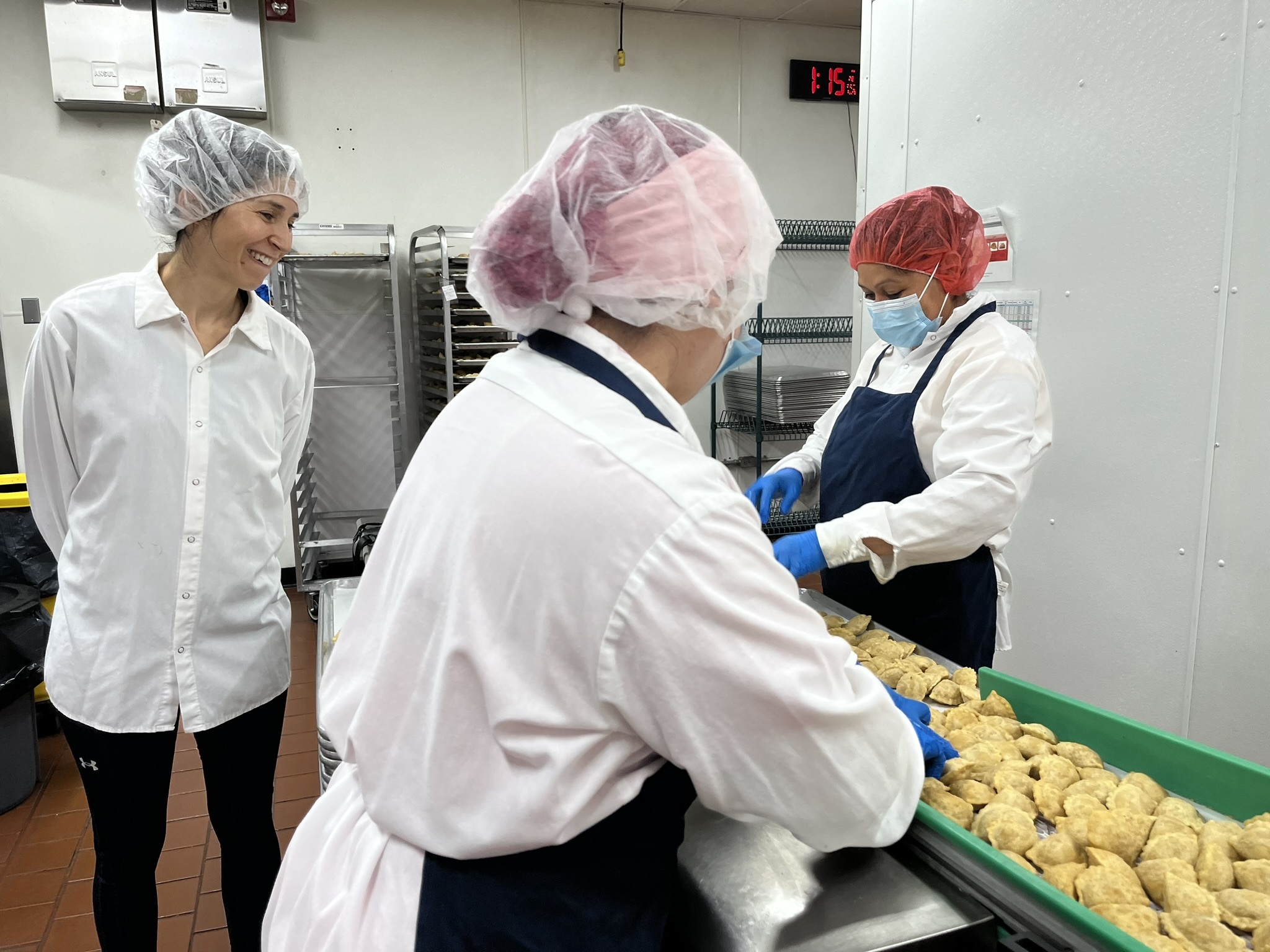 Margarita Womack, owner of the frozen empanadas company MasPanadas, (left,) looks over staffers inspecting empanadas to ensure quality control. Imperfect empanadas such as those with an uneven shape are removed and donated.