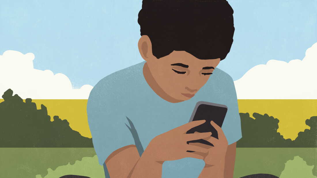 Boy sitting and using smart phone in park