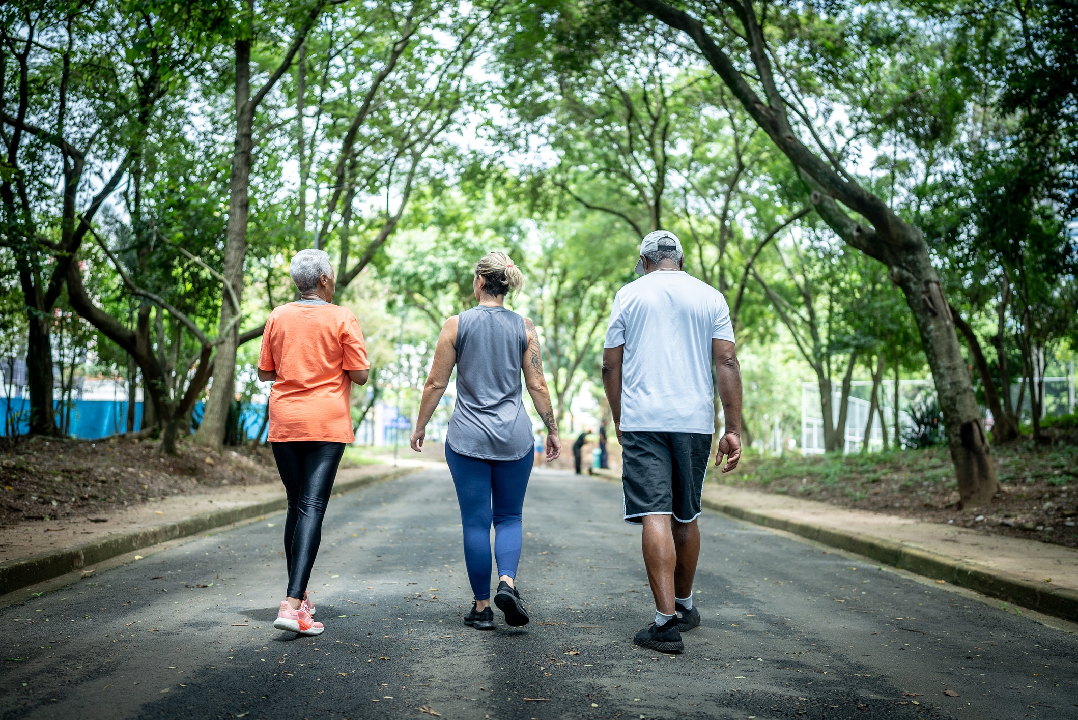 Fitness instructor walking with senior couple at public park