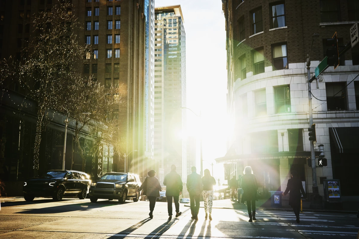 Wide shot rear view of business people crossing downtown street during evening commute