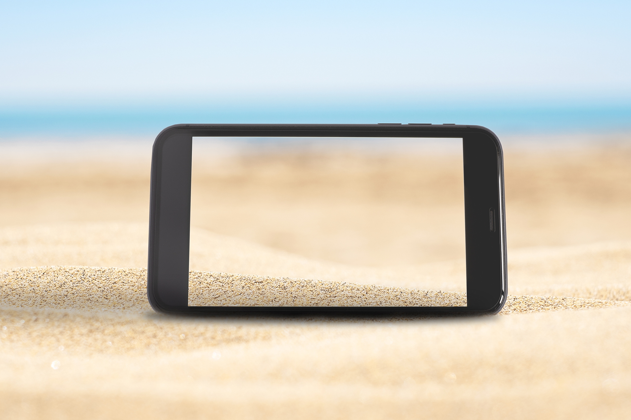 Mobile phone screen on the sandy beach with blue sea background